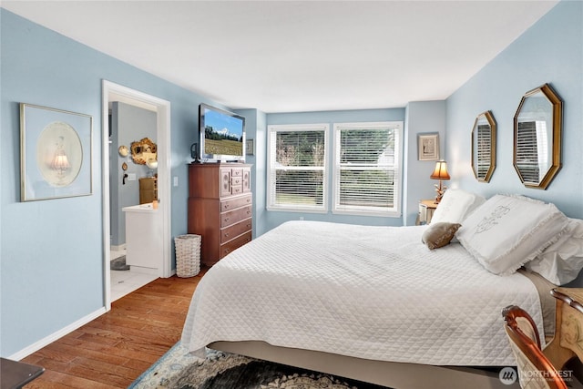 bedroom featuring connected bathroom, baseboards, and wood finished floors