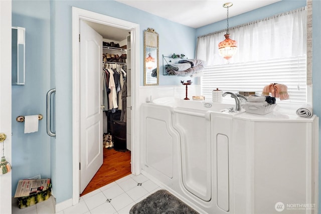 full bathroom with a bath and a spacious closet