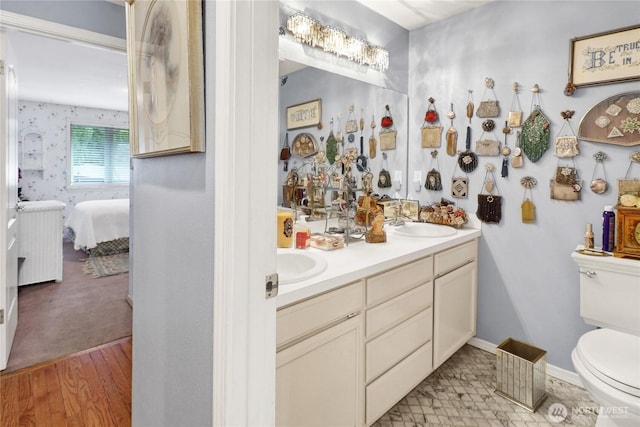 full bath with toilet, ensuite bathroom, a sink, double vanity, and baseboards