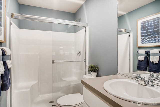 full bathroom featuring vanity, a shower stall, and toilet