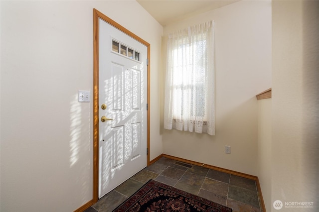 foyer entrance with baseboards and stone finish flooring