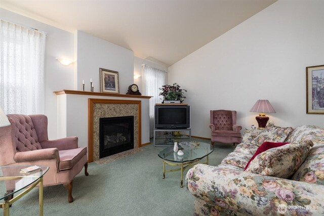 carpeted living room featuring a fireplace with flush hearth and vaulted ceiling