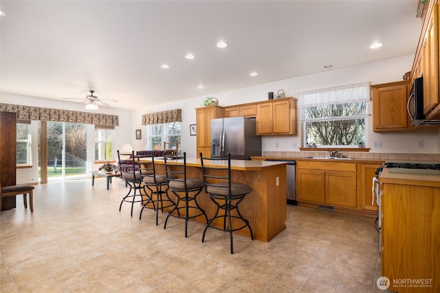 kitchen featuring a kitchen island, recessed lighting, a sink, stainless steel appliances, and a kitchen breakfast bar