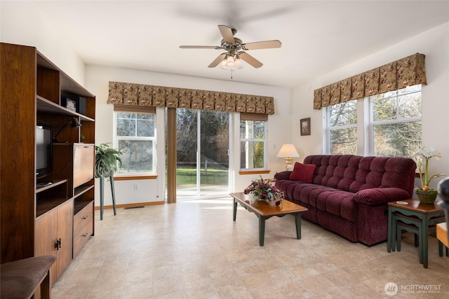 living area featuring visible vents, a ceiling fan, and baseboards