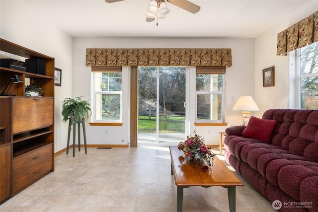 living area with visible vents, baseboards, a wealth of natural light, and ceiling fan