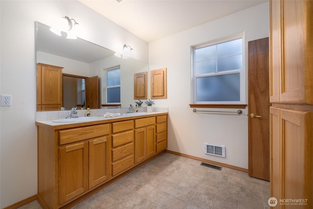 full bath featuring double vanity, baseboards, visible vents, and a sink