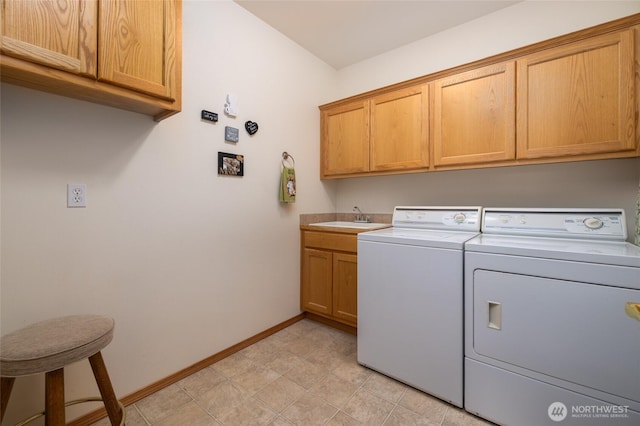 clothes washing area with a sink, baseboards, cabinet space, and washer and clothes dryer