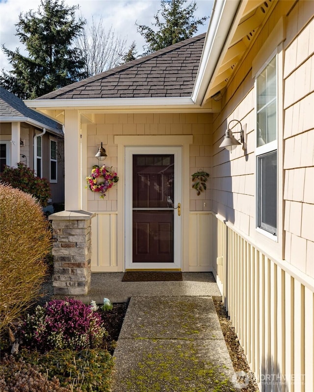 view of exterior entry with a shingled roof