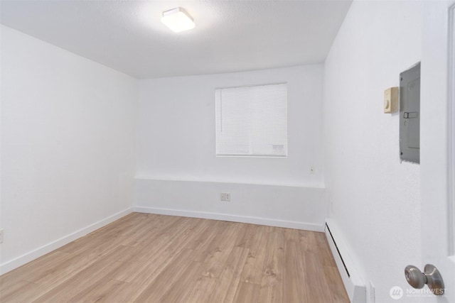 unfurnished room featuring electric panel, baseboards, light wood-type flooring, and a baseboard radiator