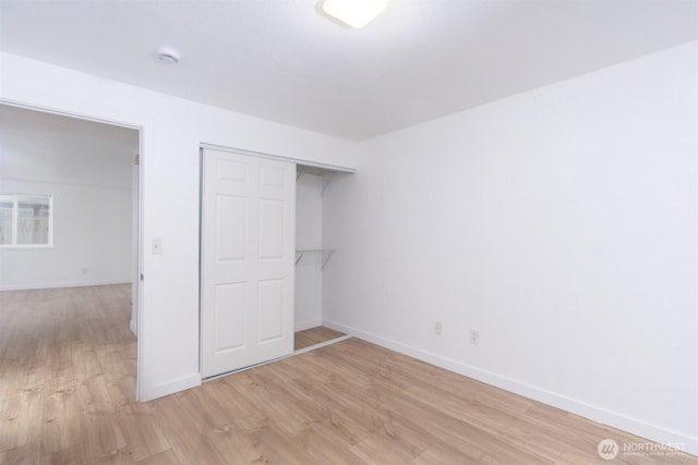 unfurnished bedroom with a closet, baseboards, and light wood finished floors