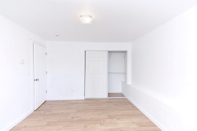 unfurnished bedroom featuring a closet, baseboards, and light wood-style floors