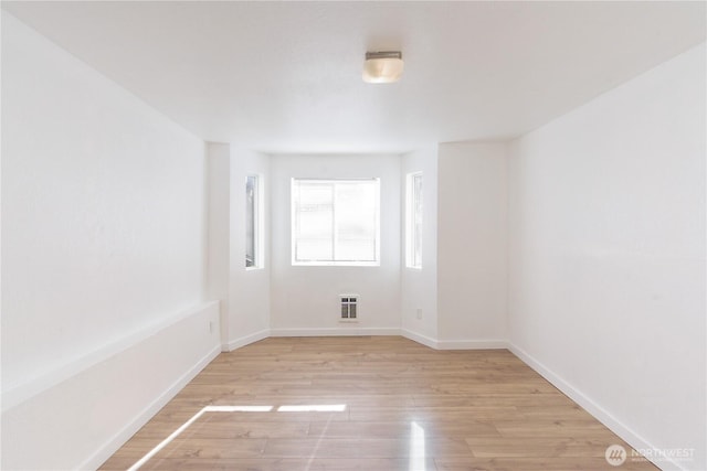 empty room featuring heating unit, light wood-type flooring, and baseboards