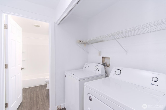 laundry area featuring laundry area, washing machine and dryer, visible vents, and wood finished floors