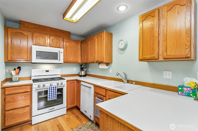 kitchen with light wood-style flooring, white appliances, light countertops, and a sink