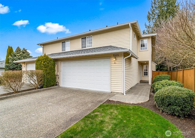 traditional-style house featuring an attached garage, fence, and driveway