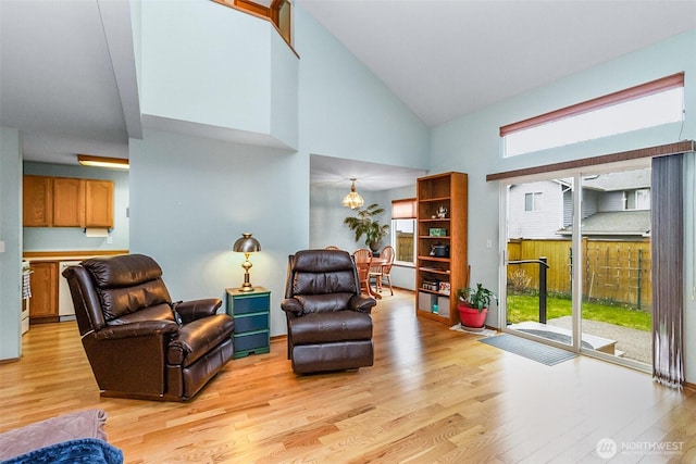 living area with light wood-type flooring, a wealth of natural light, and high vaulted ceiling