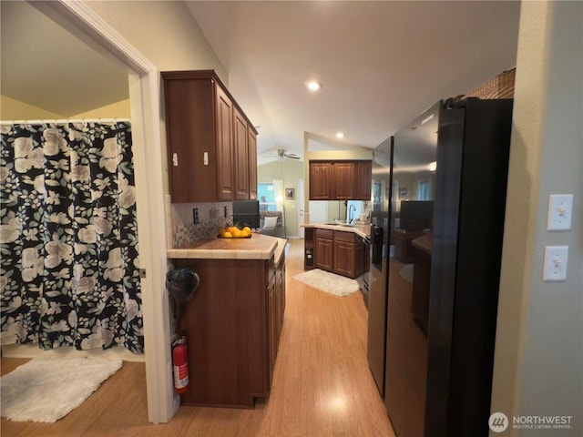 kitchen featuring freestanding refrigerator, recessed lighting, light wood finished floors, lofted ceiling, and light countertops