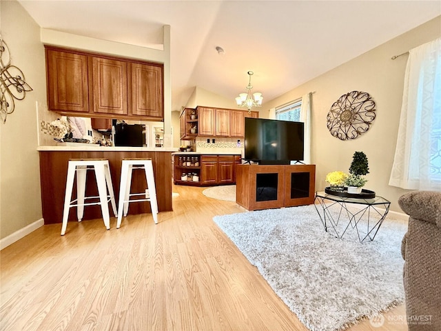 living room with light wood-style flooring, baseboards, lofted ceiling, and a chandelier