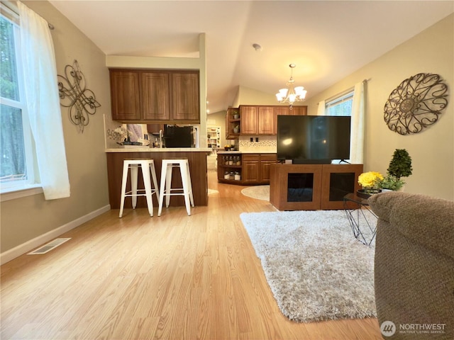 kitchen featuring brown cabinetry, visible vents, light wood finished floors, open shelves, and a notable chandelier