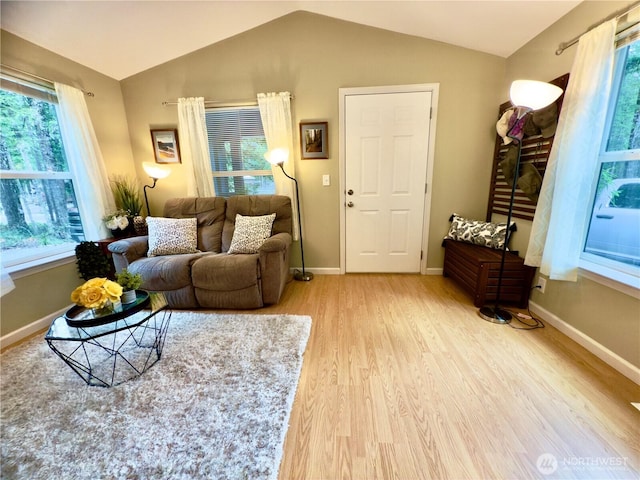 living area with lofted ceiling, wood finished floors, baseboards, and a wealth of natural light