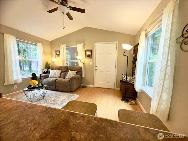 living area with vaulted ceiling, wood finished floors, baseboards, and ceiling fan