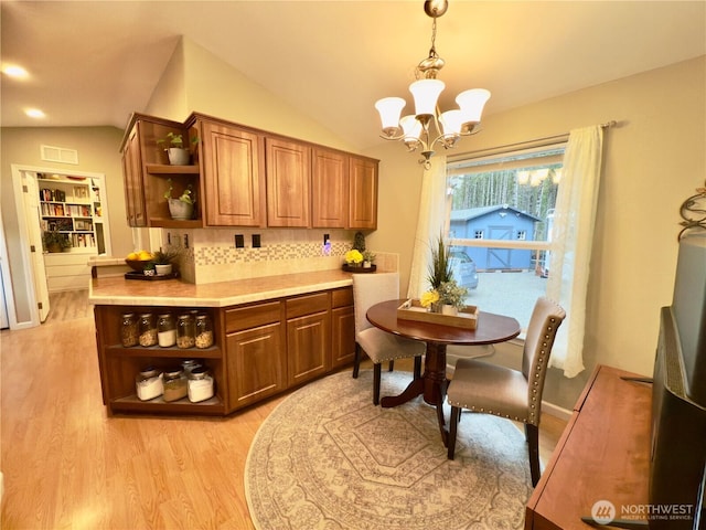 kitchen with light wood finished floors, a chandelier, vaulted ceiling, brown cabinetry, and open shelves