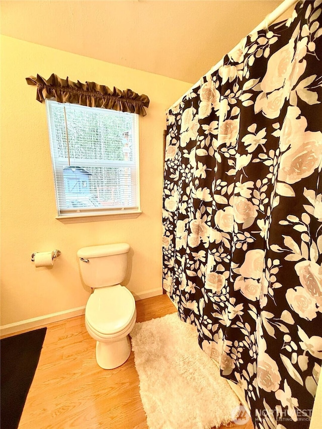 full bath featuring toilet, wood finished floors, and baseboards