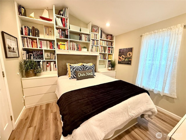 bedroom featuring wood finished floors, baseboards, and vaulted ceiling