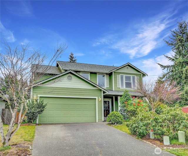 traditional-style house featuring aphalt driveway, an attached garage, and fence