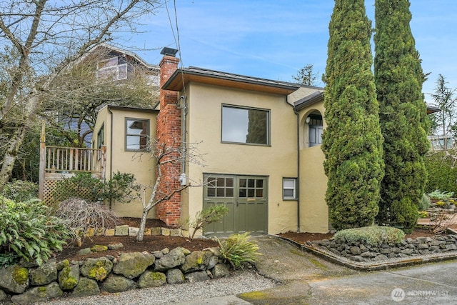 view of front of house with stucco siding and a chimney