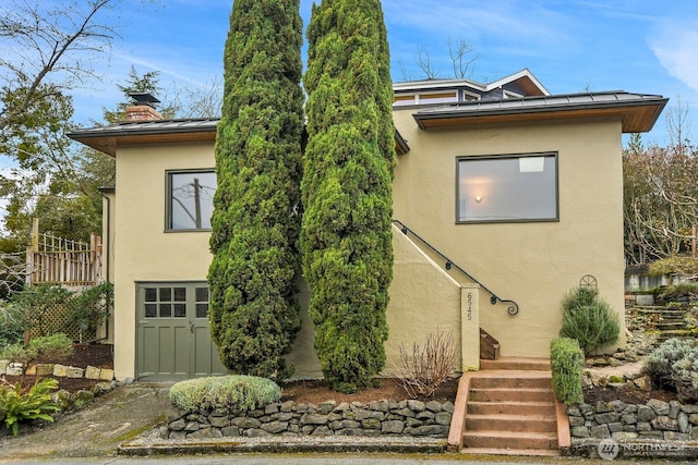 view of front of property with a chimney, stucco siding, metal roof, and a standing seam roof