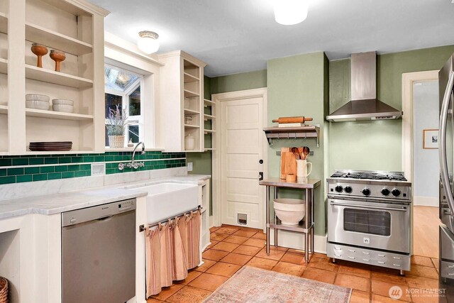 kitchen featuring open shelves, stainless steel appliances, decorative backsplash, light countertops, and wall chimney exhaust hood