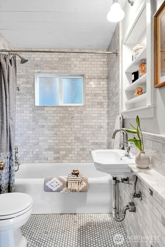 bathroom featuring tile patterned flooring, toilet, shower / tub combo with curtain, and a sink