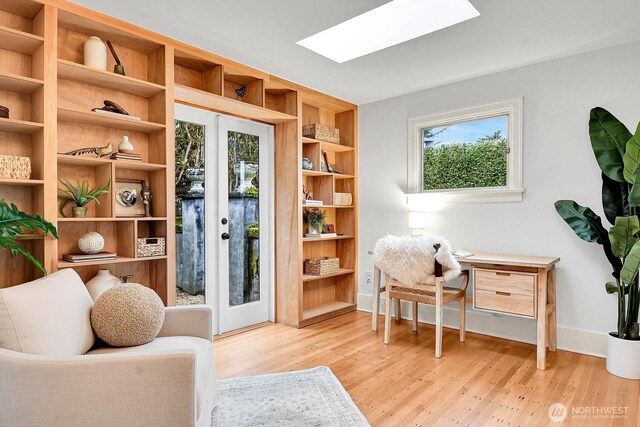 living area featuring french doors, wood finished floors, baseboards, and a skylight