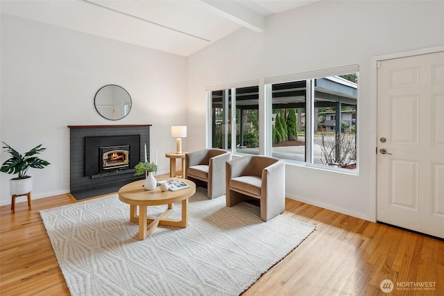 living room featuring a fireplace, vaulted ceiling with beams, baseboards, and wood finished floors