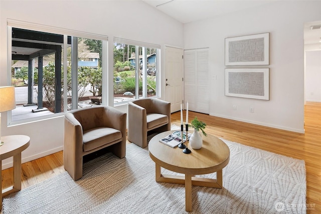 sitting room with vaulted ceiling, wood finished floors, baseboards, and visible vents