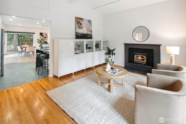 living room featuring recessed lighting, a fireplace, and wood finished floors