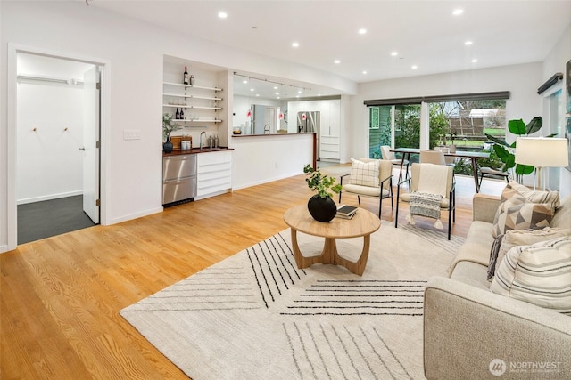 living area with recessed lighting, indoor wet bar, baseboards, and wood finished floors