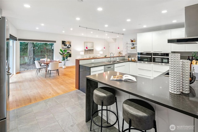 kitchen featuring dark countertops, extractor fan, a peninsula, stainless steel appliances, and modern cabinets