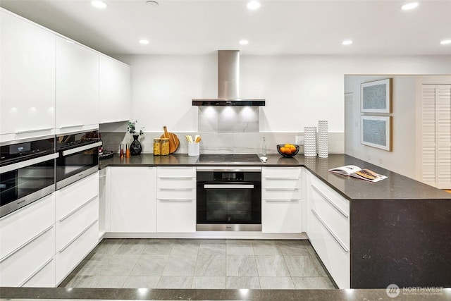 kitchen with black appliances, dark countertops, white cabinetry, a peninsula, and exhaust hood