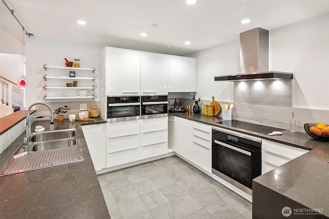 kitchen with a sink, black appliances, dark countertops, wall chimney range hood, and modern cabinets