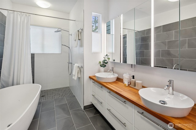 bathroom featuring tile patterned floors, a soaking tub, tiled shower, and a sink