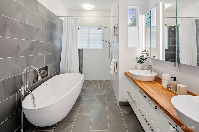 full bath featuring a sink, tile walls, double vanity, tiled shower, and a soaking tub