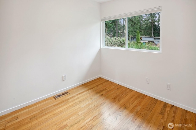 spare room with visible vents, baseboards, and wood finished floors