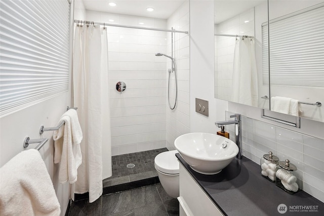 bathroom with a tile shower, toilet, tasteful backsplash, and a sink