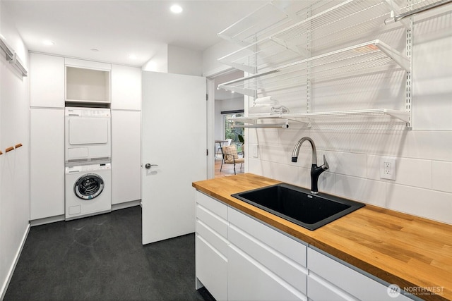 washroom with laundry area, recessed lighting, stacked washer / drying machine, and a sink