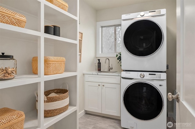 clothes washing area with cabinet space, stacked washer / drying machine, and a sink