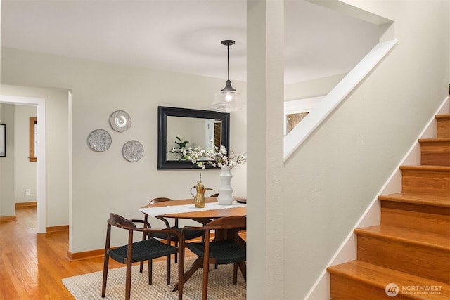 dining space featuring stairs, baseboards, and wood finished floors