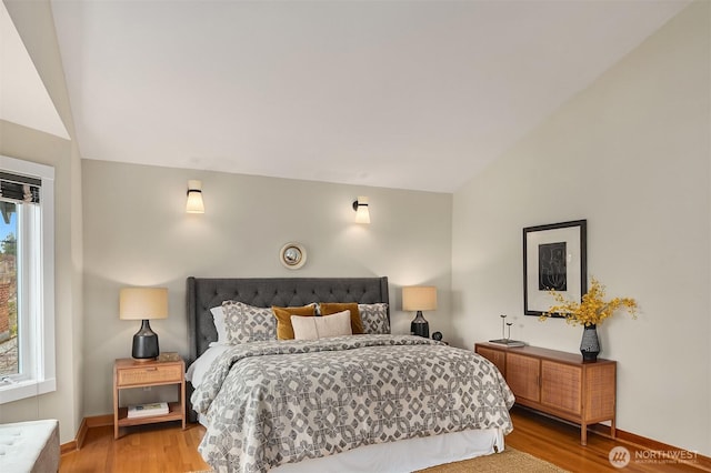 bedroom with vaulted ceiling, light wood-style flooring, and baseboards