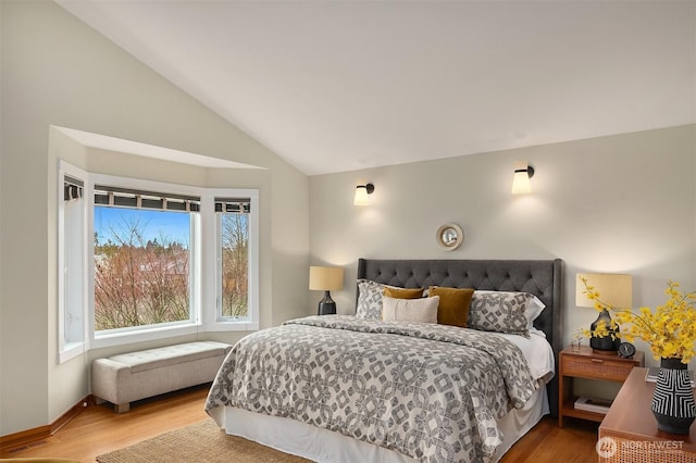 bedroom with visible vents, baseboards, lofted ceiling, and wood finished floors